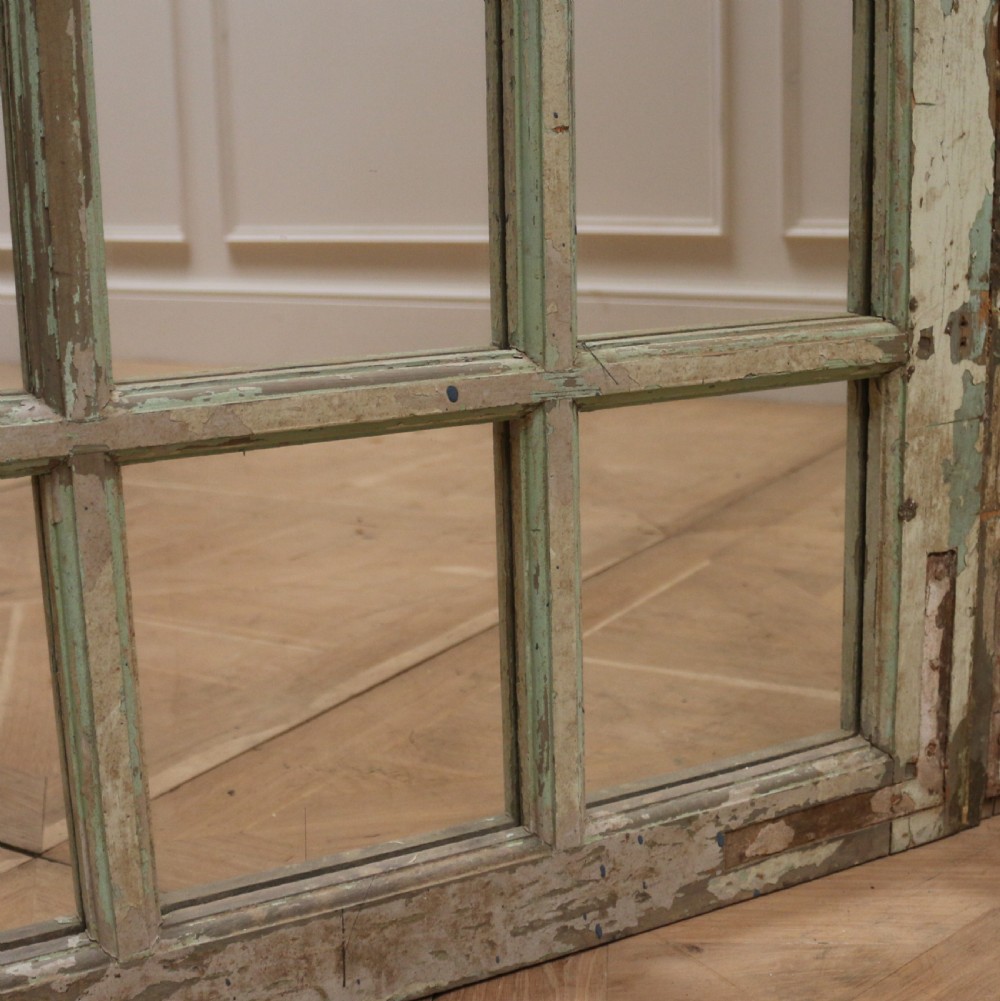 A large semi-circular arched architectural window frame with distressed green paint finish converted into a multi-pane mirror. View III
