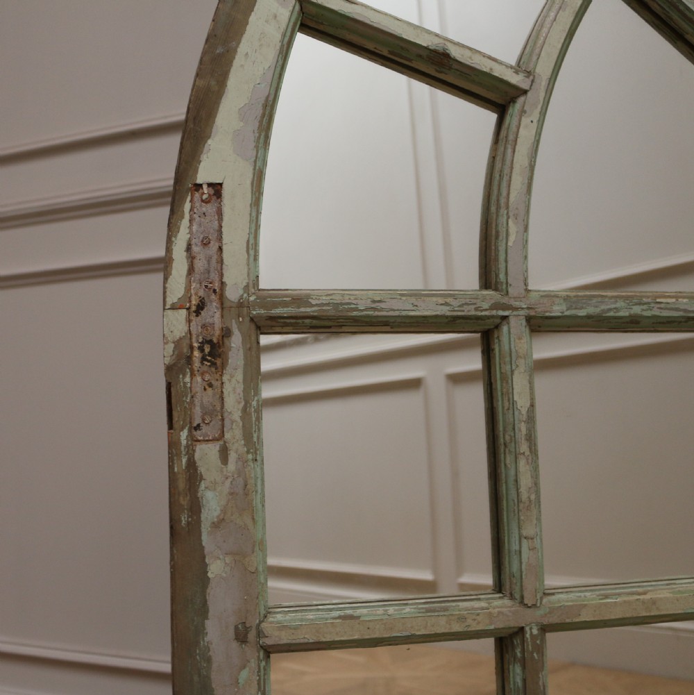 A large semi-circular arched architectural window frame with distressed green paint finish converted into a multi-pane mirror. View IV
