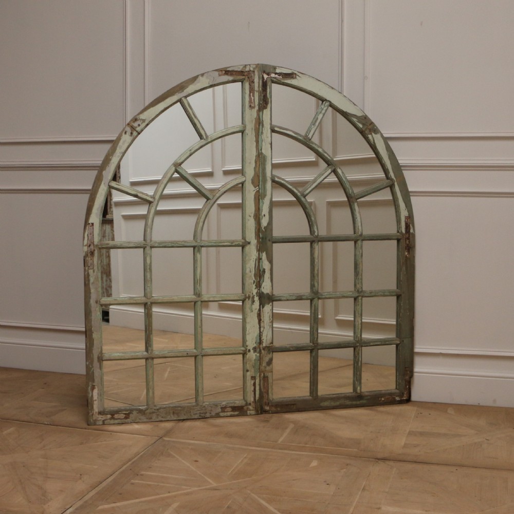 A large semi-circular arched architectural window frame with distressed green paint finish converted into a multi-pane mirror. View V