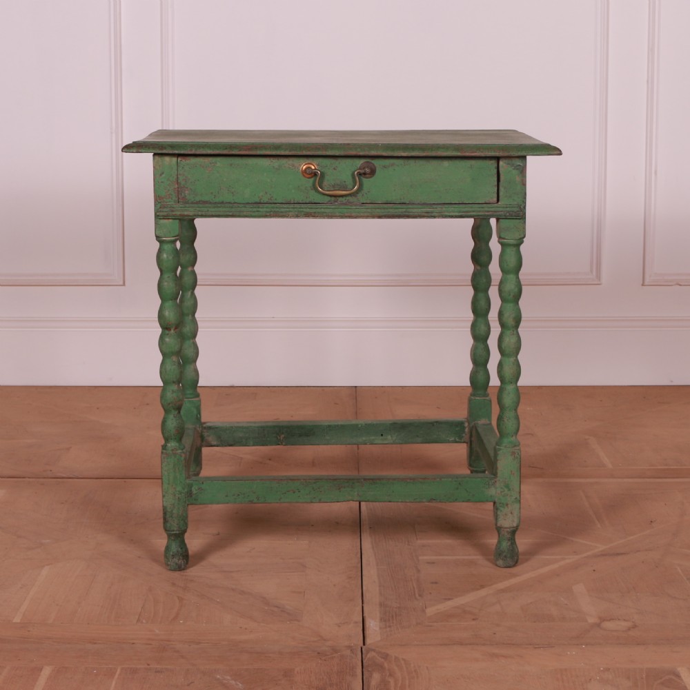 An 18th-century green painted wooden lamp table featuring four bobbin-turned legs, a rectangular top, lower stretchers, and a single drawer with a brass drop handle.