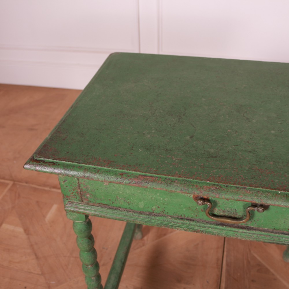 An 18th-century green painted wooden lamp table featuring four bobbin-turned legs, a rectangular top, lower stretchers, and a single drawer with a brass drop handle. View VII
