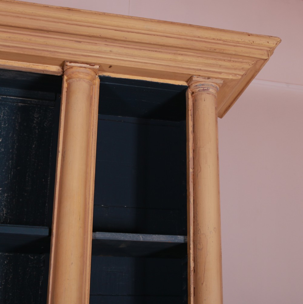 A large antique French painted bookcase featuring a pale yellow exterior, open shelving with a dark blue painted interior, and panelled cupboard doors at the base. View IX