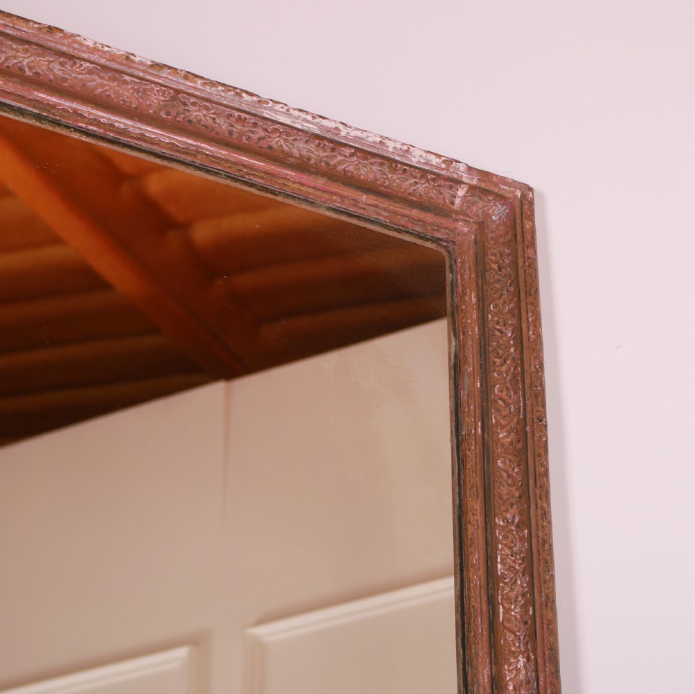 A large rectangular floor-leaning mirror featuring a distressed reddish-brown painted wooden frame and a clear reflective plate. View IV