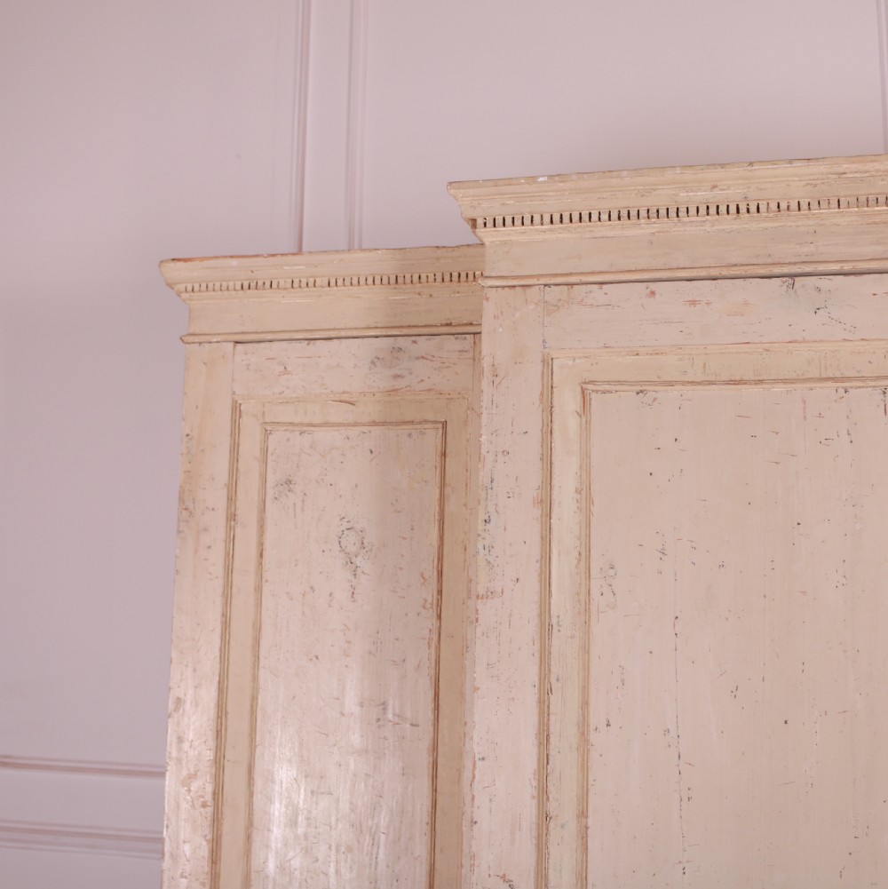 An antique cream-painted breakfront housekeepers cupboard featuring central panelled doors above drawers, flanked by tall side cupboards. View II