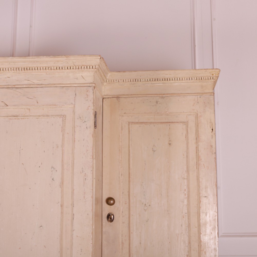 An antique cream-painted breakfront housekeepers cupboard featuring central panelled doors above drawers, flanked by tall side cupboards. View IV