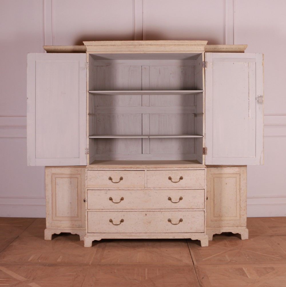 An antique cream-painted breakfront housekeepers cupboard featuring central panelled doors above drawers, flanked by tall side cupboards. View VI