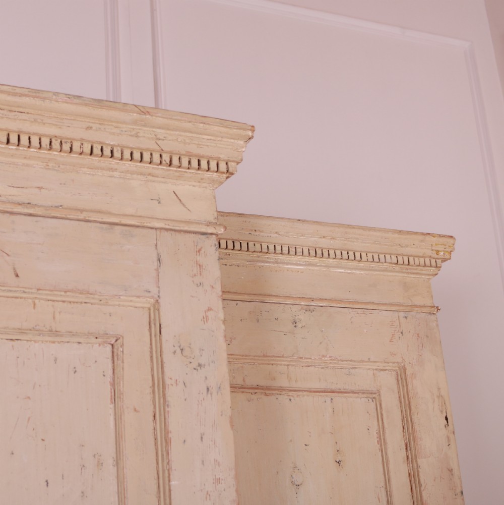 An antique cream-painted breakfront housekeepers cupboard featuring central panelled doors above drawers, flanked by tall side cupboards. View VII