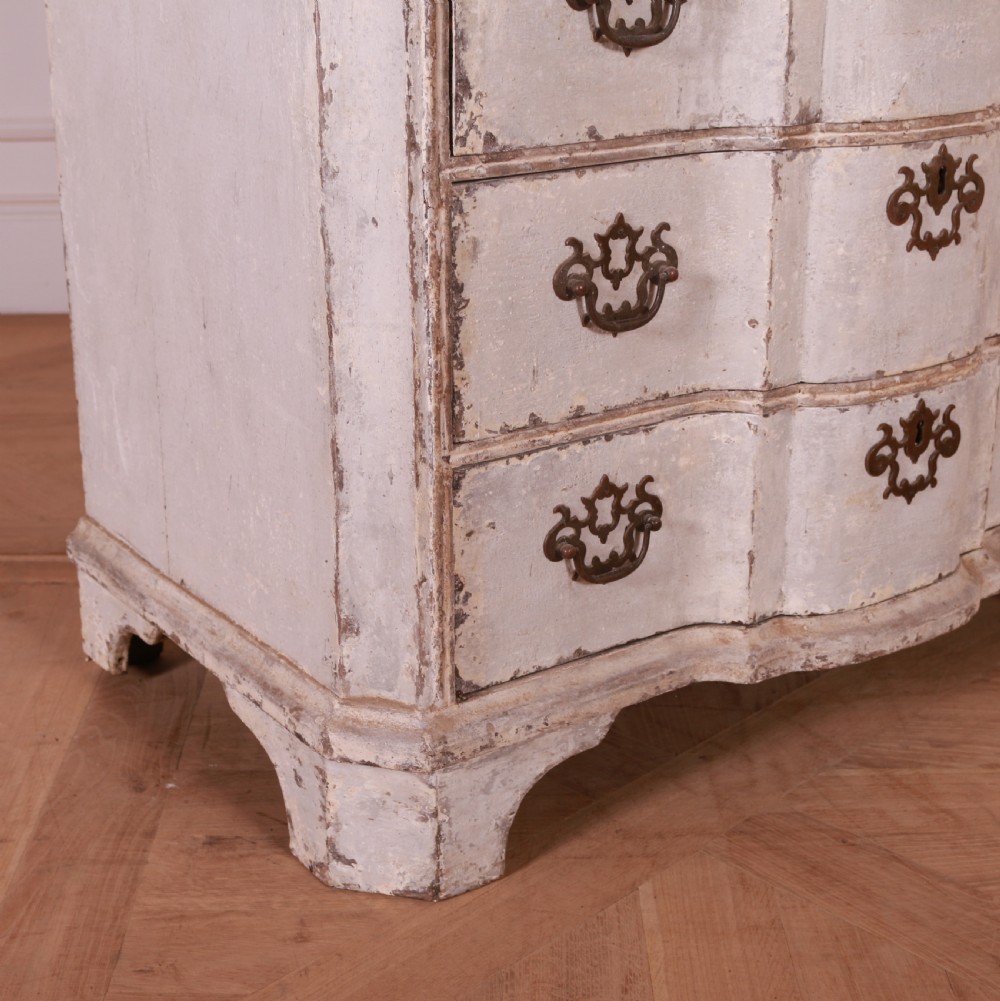 An 18th-century Dutch serpentine-front commode featuring four drawers with a distressed pale paint finish and ornate brass handles. View III