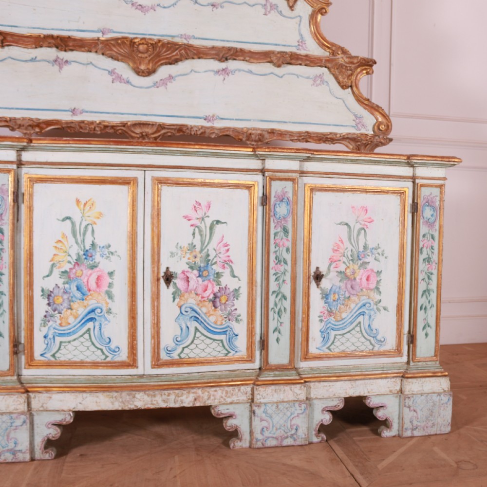 An 18th-century Italian painted credenza featuring four floral-panel doors, giltwood mouldings, and a matching stepped shelf structure mounted above. View III