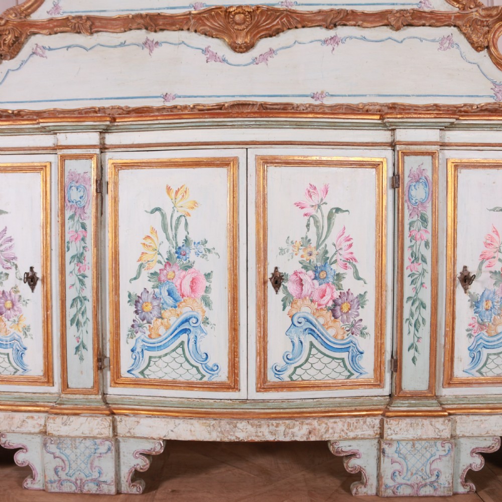 An 18th-century Italian painted credenza featuring four floral-panel doors, giltwood mouldings, and a matching stepped shelf structure mounted above. View IV