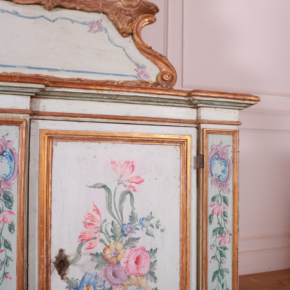 An 18th-century Italian painted credenza featuring four floral-panel doors, giltwood mouldings, and a matching stepped shelf structure mounted above. View VI