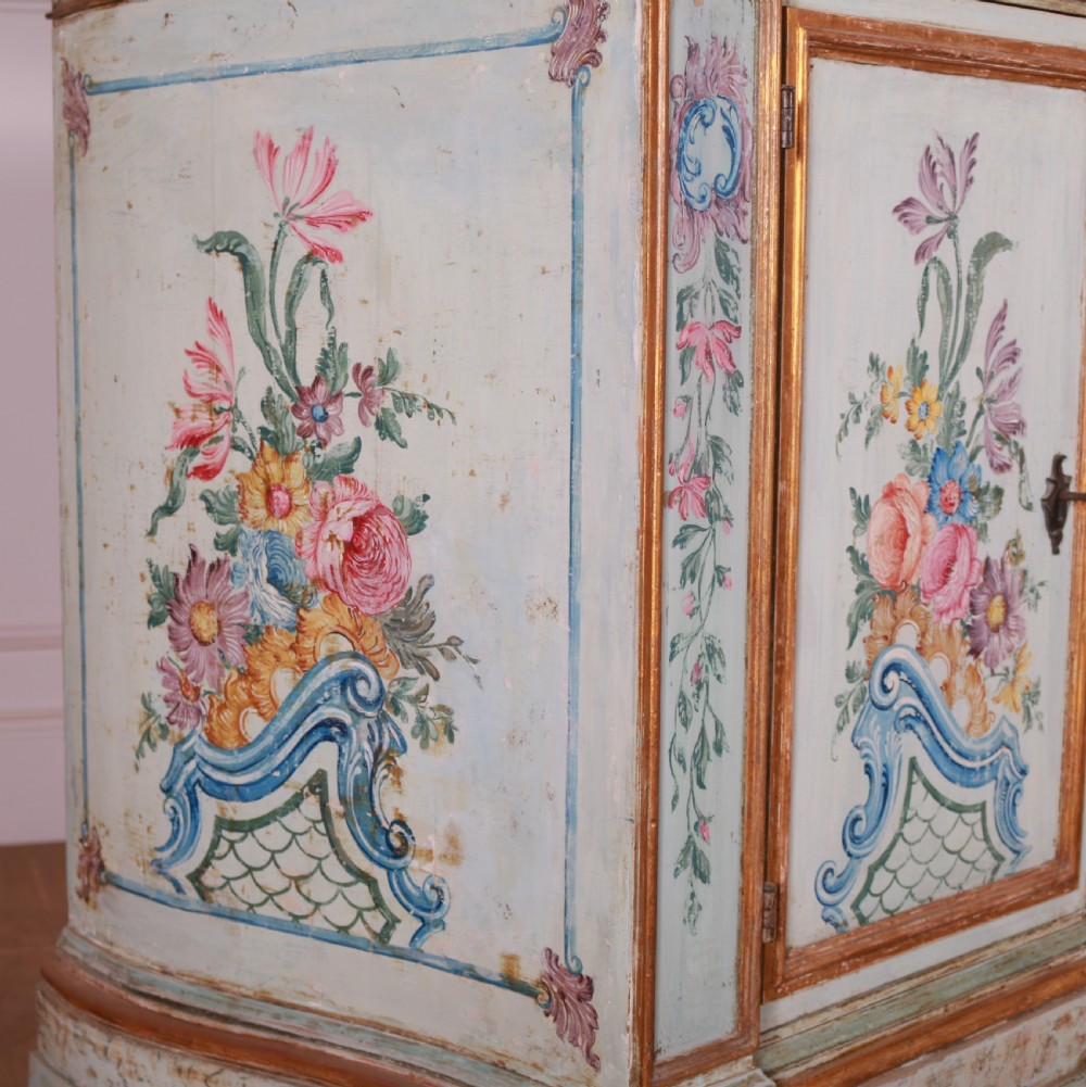 An 18th-century Italian painted credenza featuring four floral-panel doors, giltwood mouldings, and a matching stepped shelf structure mounted above. View XII