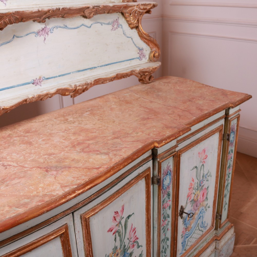 An 18th-century Italian painted credenza featuring four floral-panel doors, giltwood mouldings, and a matching stepped shelf structure mounted above. View XVII