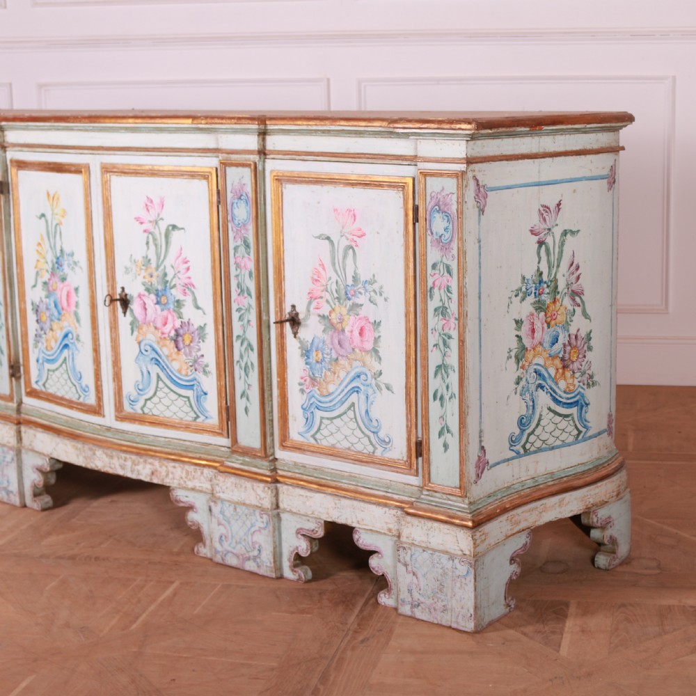 An 18th-century Italian painted credenza featuring four floral-panel doors, giltwood mouldings, and a matching stepped shelf structure mounted above. View XX
