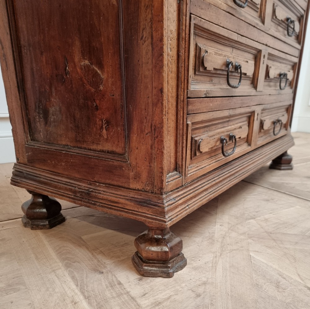 An 18th-century Italian walnut commode featuring four long drawers with geometric raised panel mouldings, iron drop handles, and octagonal feet. View VIII