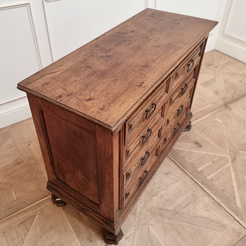An 18th-century Italian walnut commode featuring four long drawers with geometric raised panel mouldings, iron drop handles, and octagonal feet. View IX