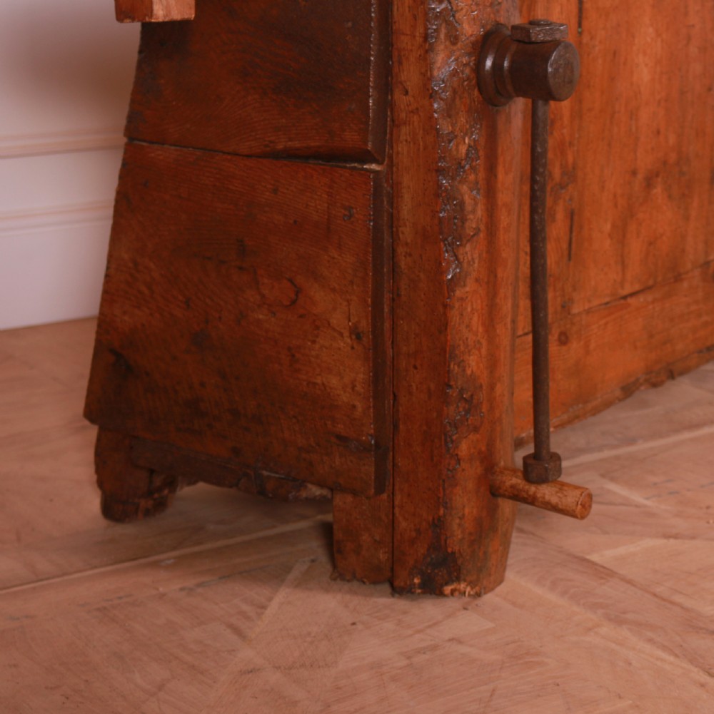 A rustic French primitive timber workbench with an integrated wooden vice mechanism and a thick slab top. View III