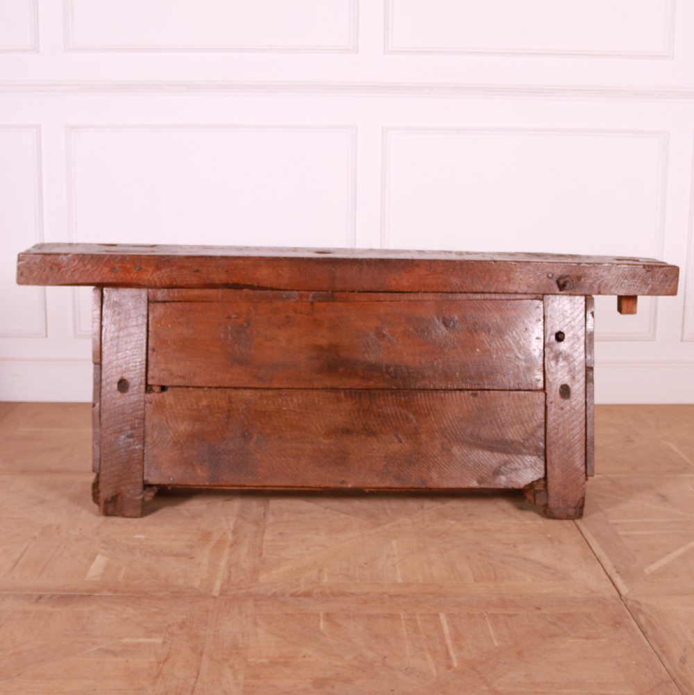 A rustic French primitive timber workbench with an integrated wooden vice mechanism and a thick slab top. View VI