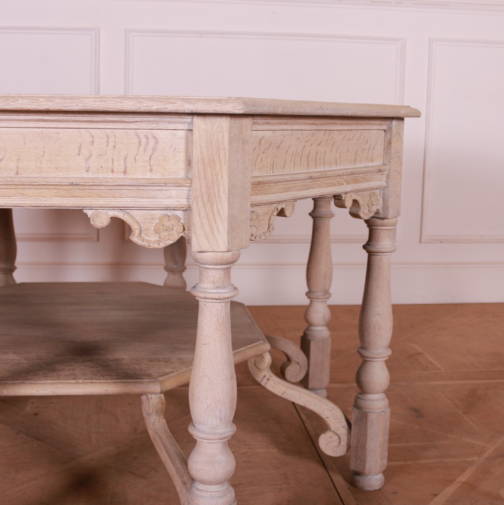 An octagonal bleached oak centre table featuring turned legs, a lower shelf, and decorative carved aprons. View II