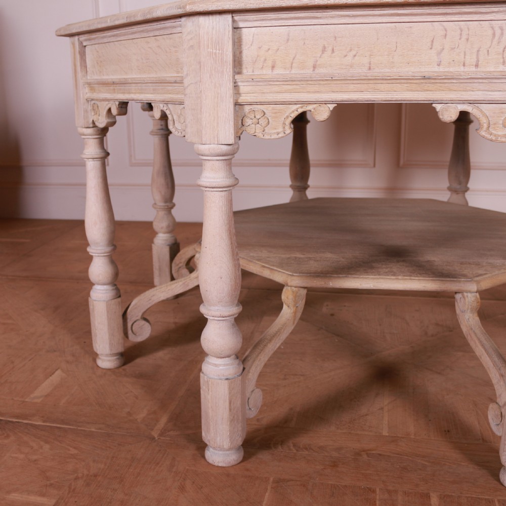 An octagonal bleached oak centre table featuring turned legs, a lower shelf, and decorative carved aprons. View IV