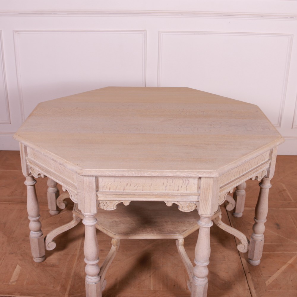 An octagonal bleached oak centre table featuring turned legs, a lower shelf, and decorative carved aprons. View V