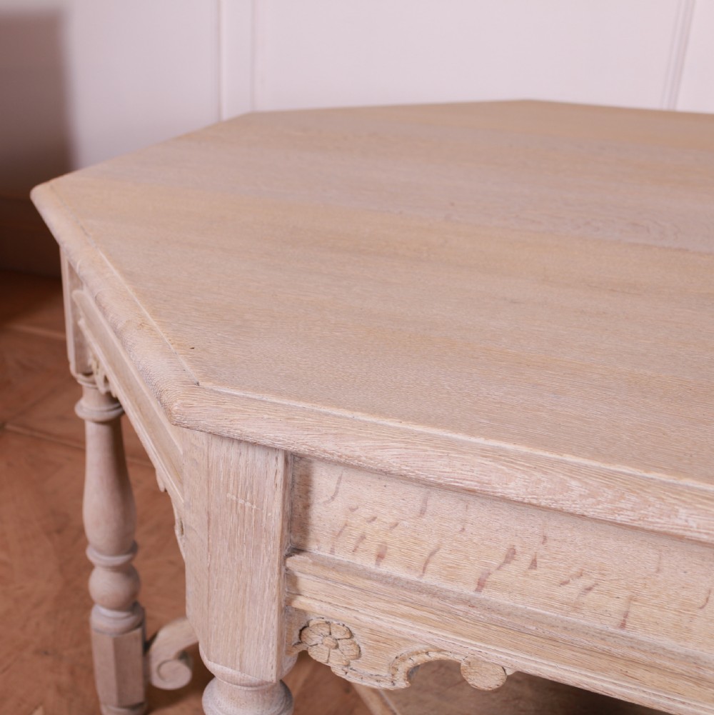 An octagonal bleached oak centre table featuring turned legs, a lower shelf, and decorative carved aprons. View VI