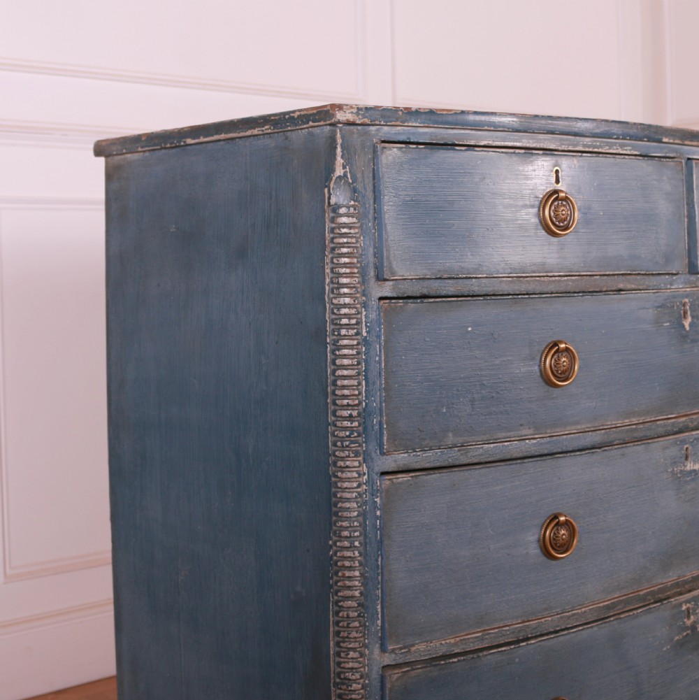 A blue painted bow-front chest of drawers featuring two small drawers over three long drawers with brass ring handles. View V