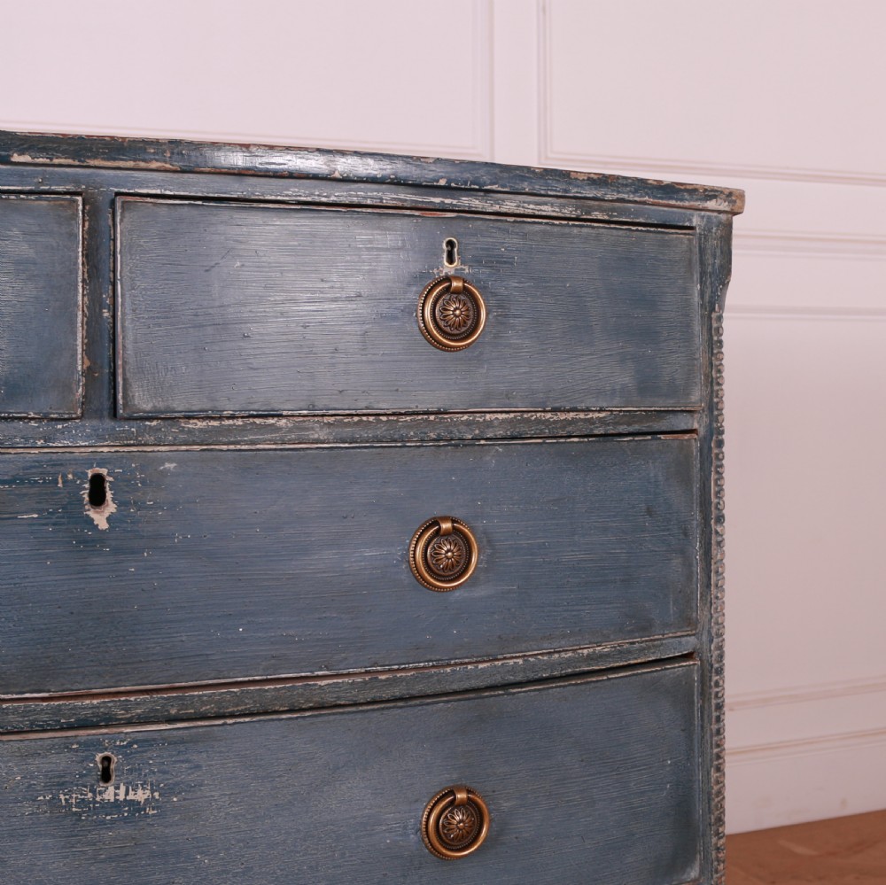 A blue painted bow-front chest of drawers featuring two small drawers over three long drawers with brass ring handles. View VI