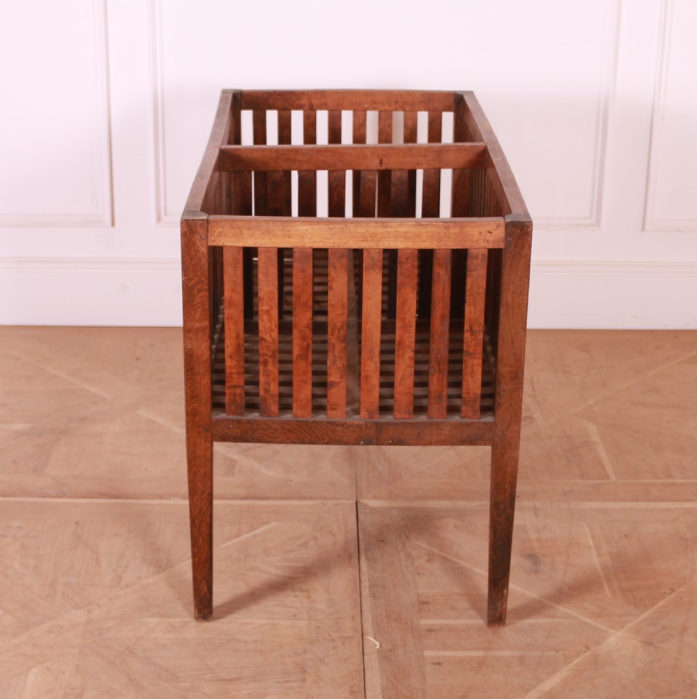 A rectangular rustic wooden log basket featuring vertical slatted sides, a central interior divider, and four tapered legs. View III