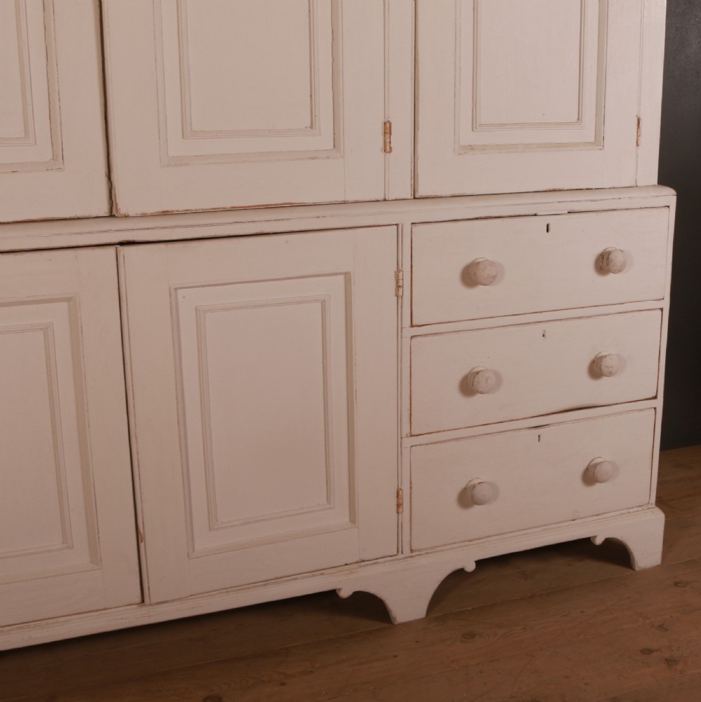 A large two-part off-white painted pine housekeepers cupboard with four upper fielded panel doors, six flanking drawers, and two central lower cabinet doors. View III