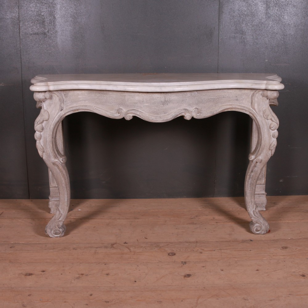 An off-white carved wooden console table with a serpentine white marble top and cabriole legs.