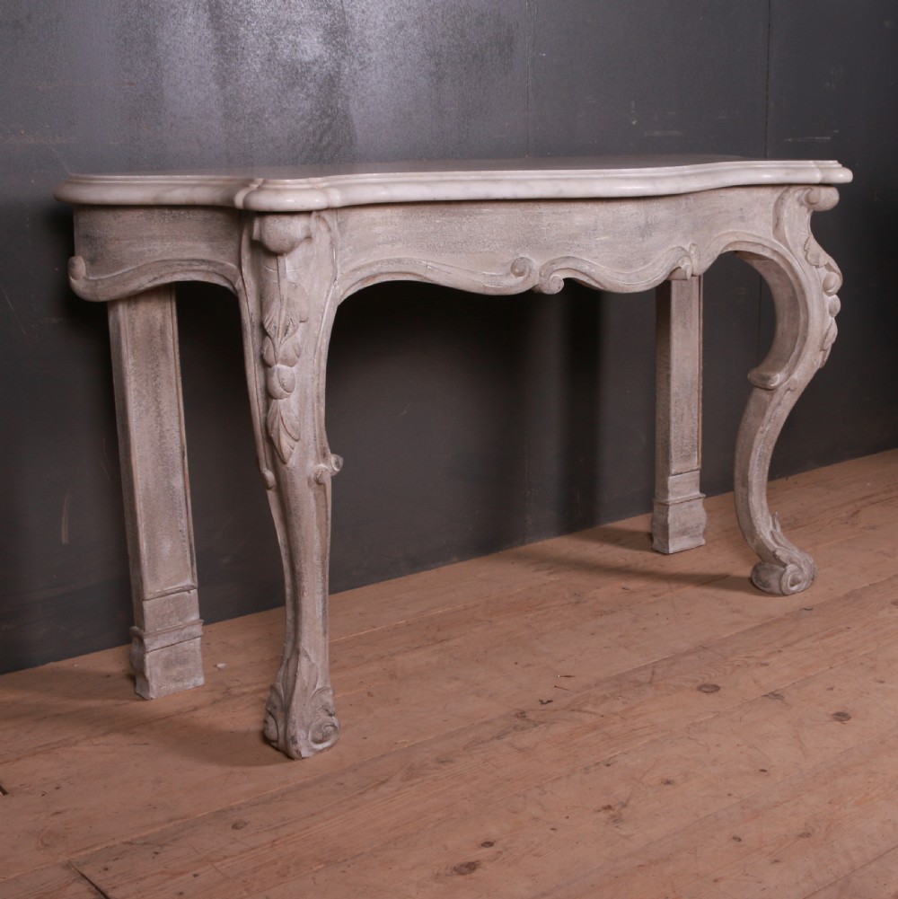 An off-white carved wooden console table with a serpentine white marble top and cabriole legs. View II