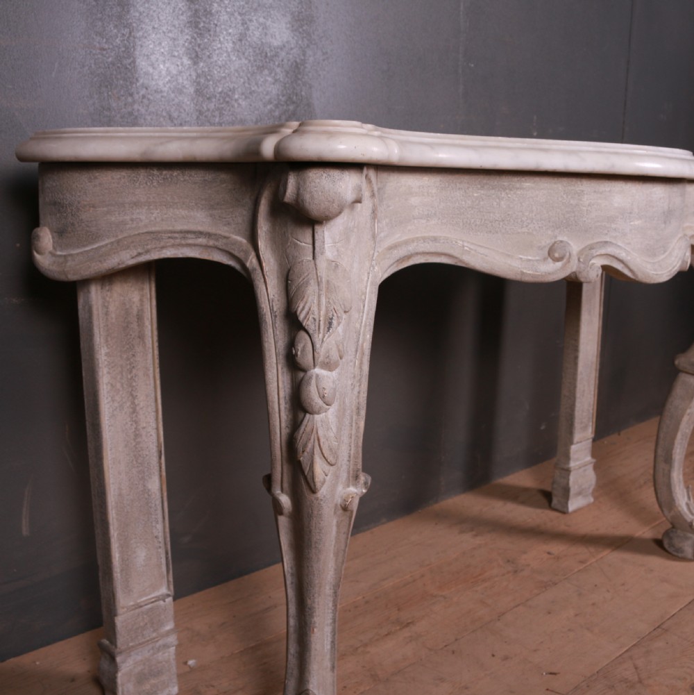 An off-white carved wooden console table with a serpentine white marble top and cabriole legs. View VI