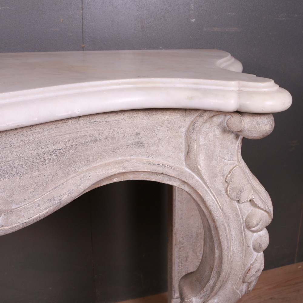 An off-white carved wooden console table with a serpentine white marble top and cabriole legs. View IX
