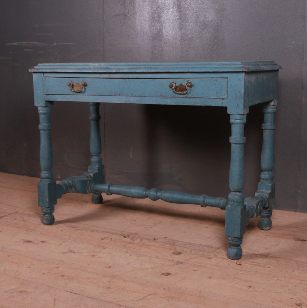 A blue painted side table featuring a single drawer with two brass handles, turned legs, and lower stretchers.