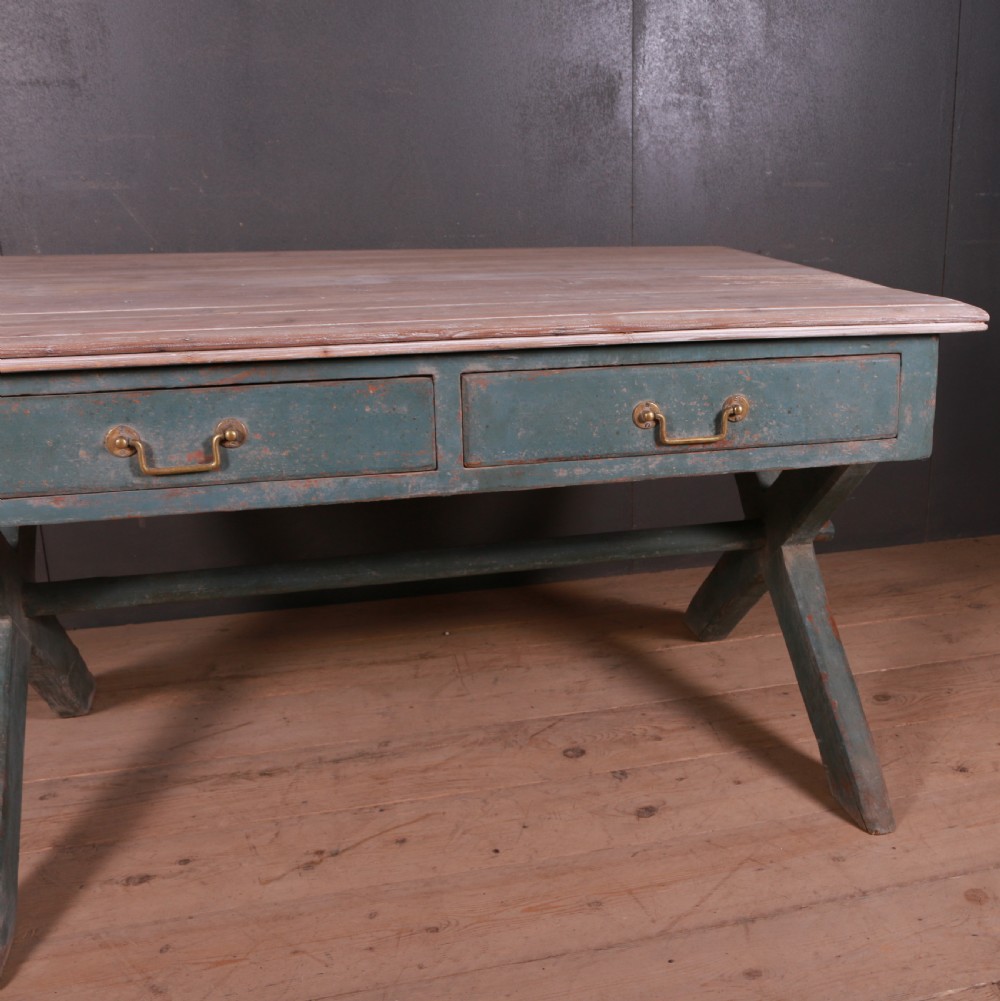 An antique English trestle table featuring a muted teal painted X-frame base, two apron drawers with brass handles, and a scrubbed natural pine top. View VI