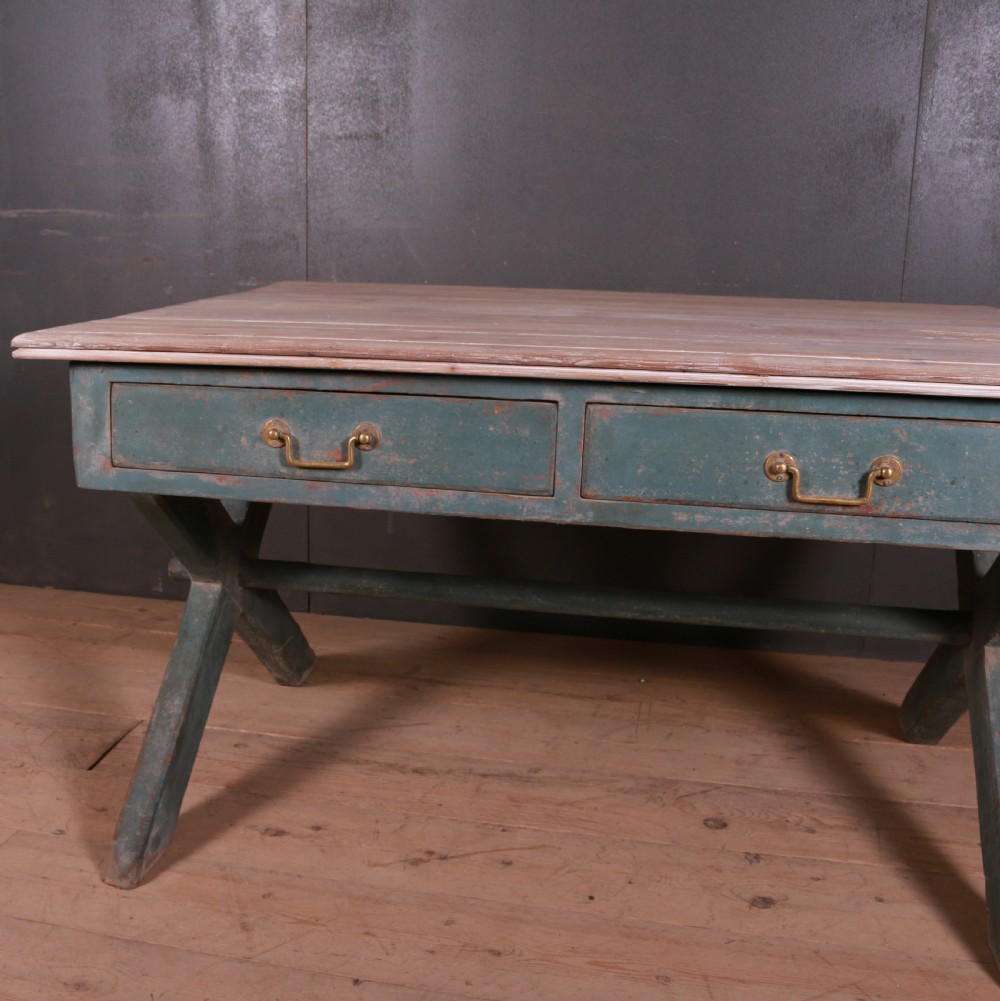 An antique English trestle table featuring a muted teal painted X-frame base, two apron drawers with brass handles, and a scrubbed natural pine top. View VII