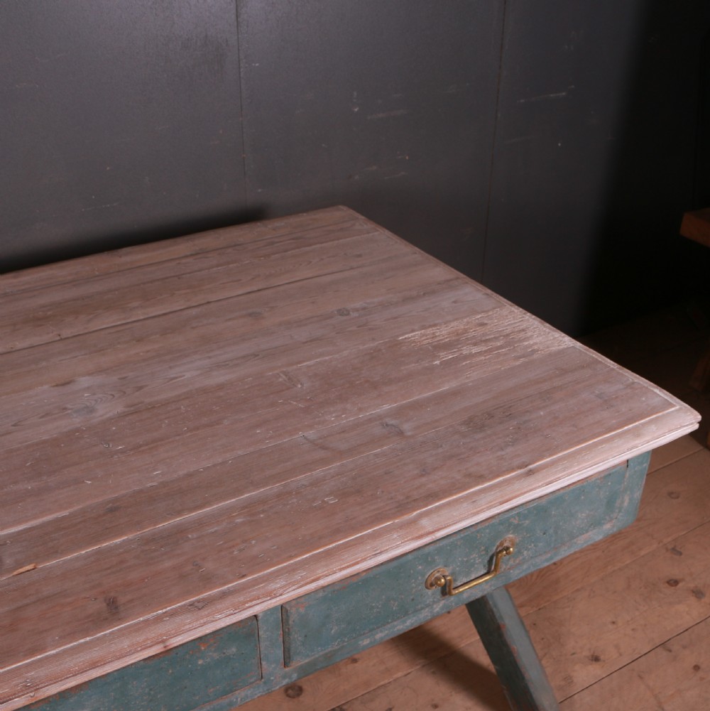 An antique English trestle table featuring a muted teal painted X-frame base, two apron drawers with brass handles, and a scrubbed natural pine top. View IX