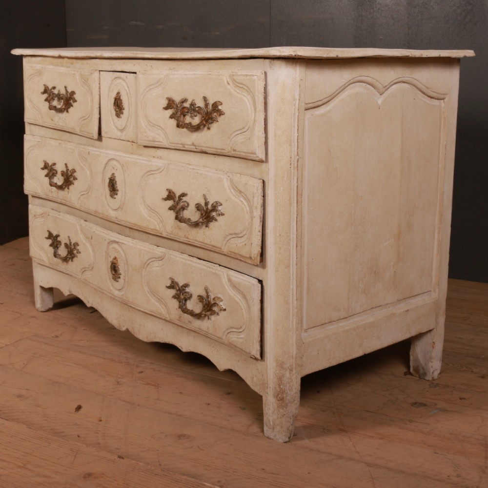 An off-white painted wooden French commode featuring three drawers with ornamental brass handles and a scalloped bottom apron. View VI