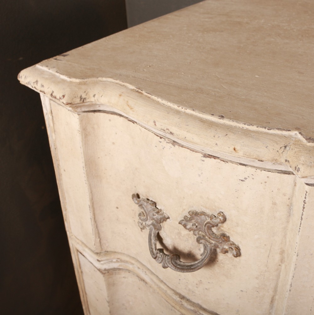 An off-white painted Danish serpentine front commode featuring four drawers with ornate hardware on short cabriole legs. View VII
