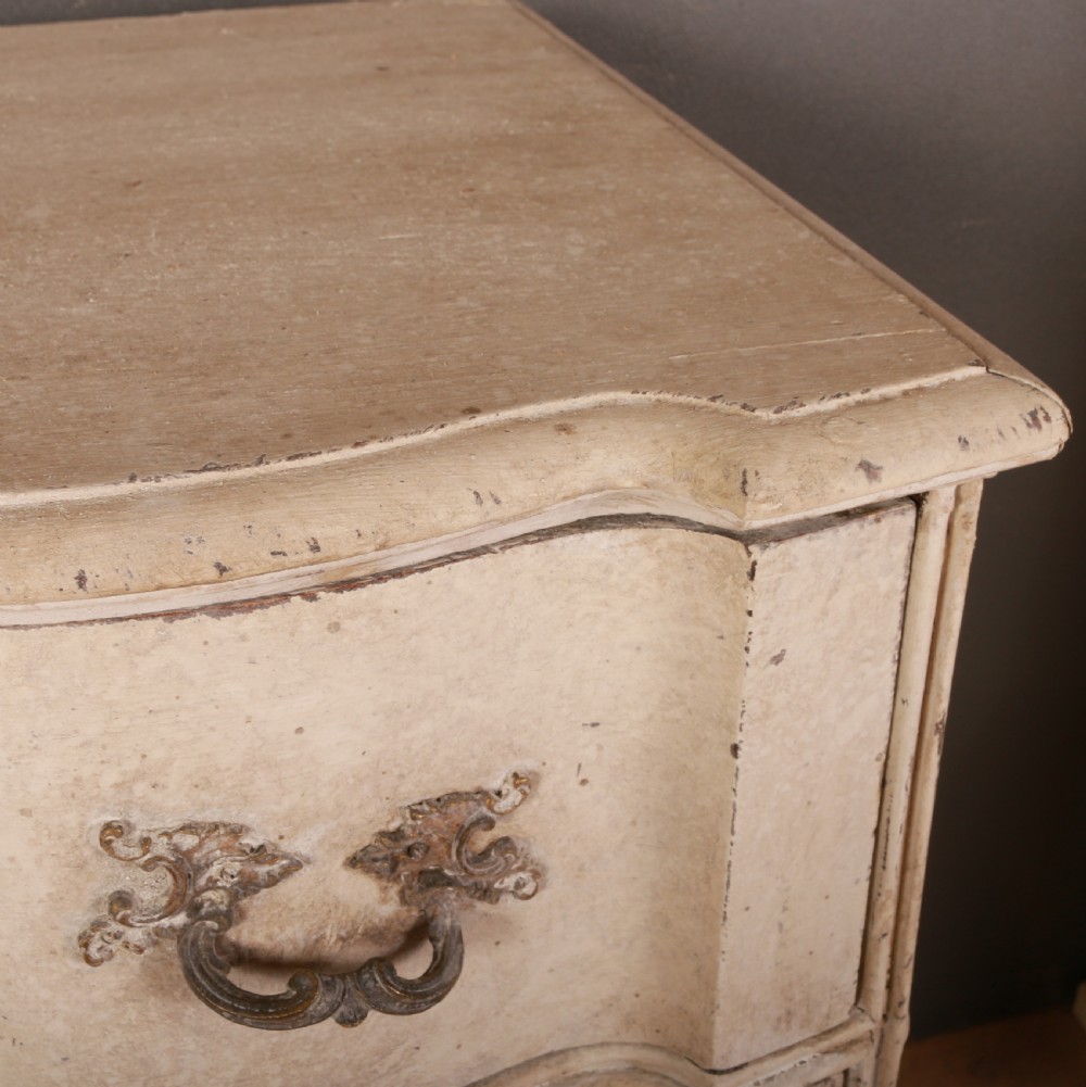 An off-white painted Danish serpentine front commode featuring four drawers with ornate hardware on short cabriole legs. View VIII