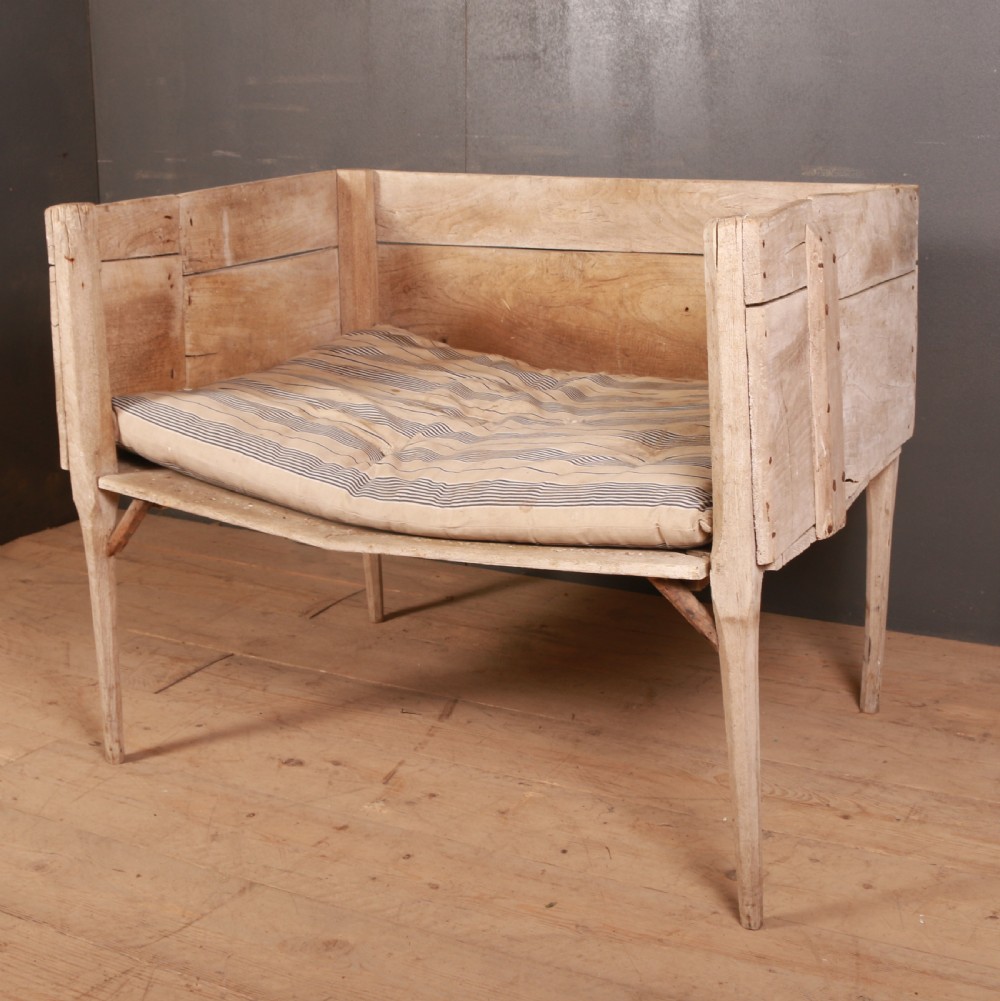 An elevated rustic wooden dog bed with three high panelled sides, straight legs, and a striped fabric cushion. View II