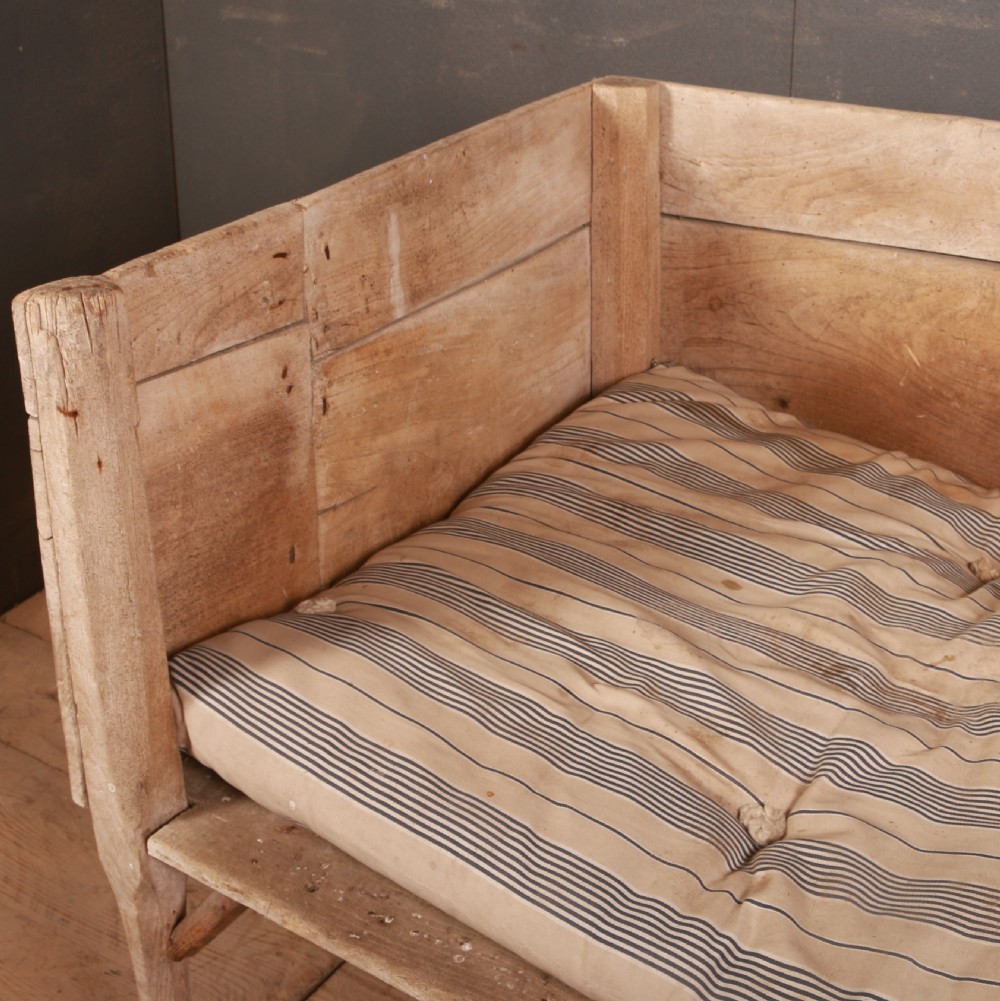 An elevated rustic wooden dog bed with three high panelled sides, straight legs, and a striped fabric cushion. View IV