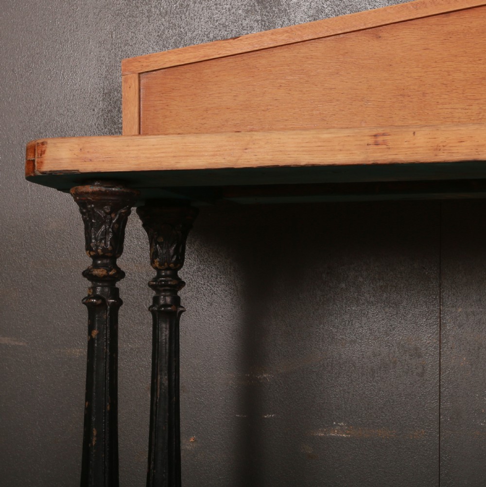 An antique bleached oak console table featuring a pediment backboard with a central carved motif, dark ebonised turned columns, and a carved lower plinth. View VII