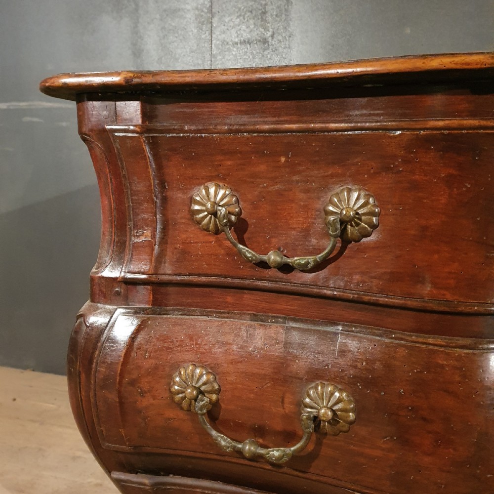 A French walnut commode featuring a serpentine front, three drawers with brass handles, and short cabriole legs. View VI
