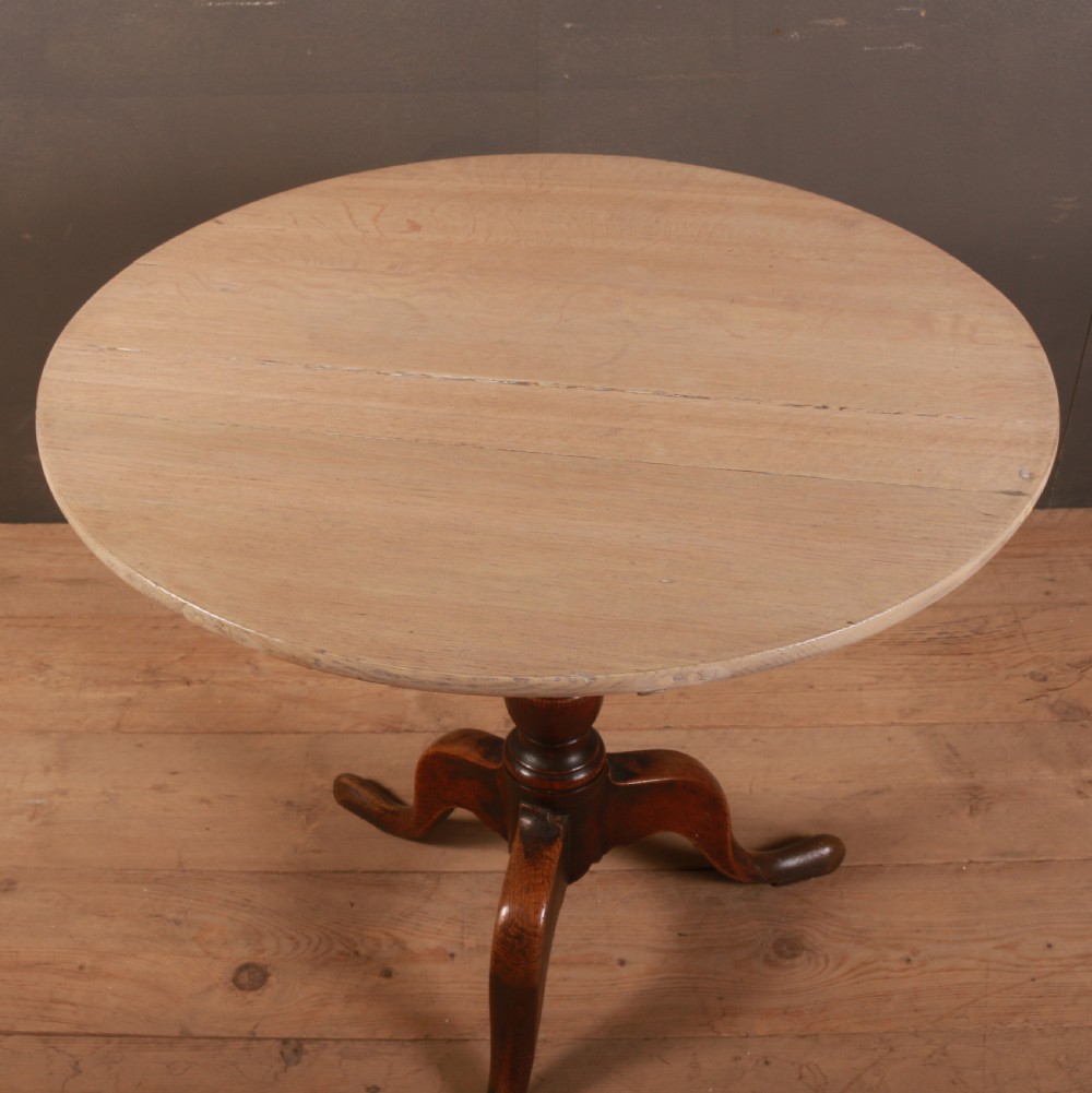 A Georgian oak tripod table featuring a light scrubbed circular top resting on a dark turned central column with three pad-footed cabriole legs. View III