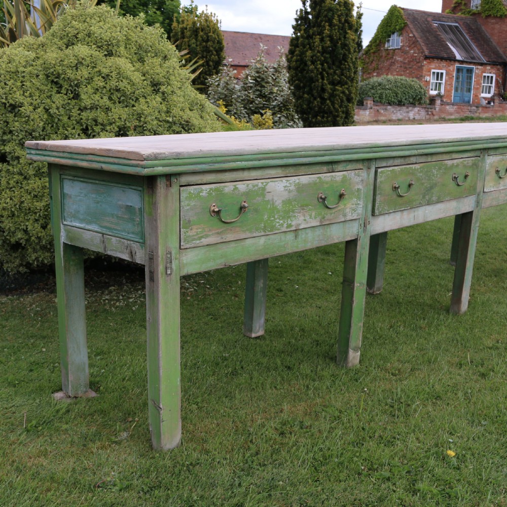 An exceptionally long antique English dresser base featuring a distressed green painted finish, multiple drawers with drop handles, and square legs. View III
