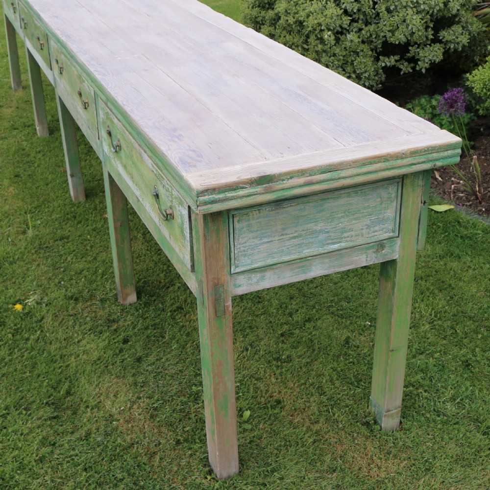 An exceptionally long antique English dresser base featuring a distressed green painted finish, multiple drawers with drop handles, and square legs. View VII