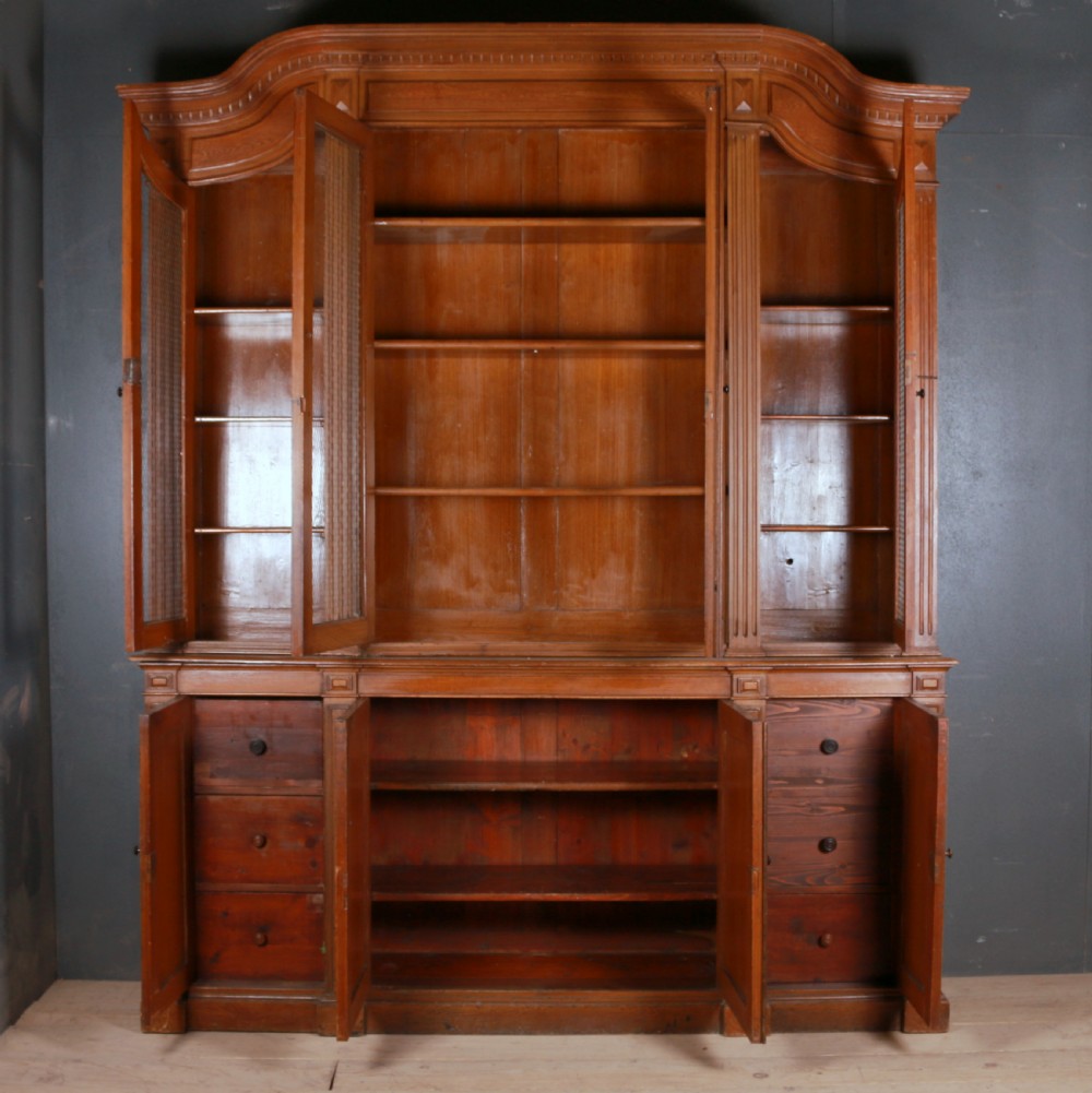 A large antique French oak bookcase with four wire mesh upper doors and four panelled lower doors featuring a shaped moulded cornice. View VII