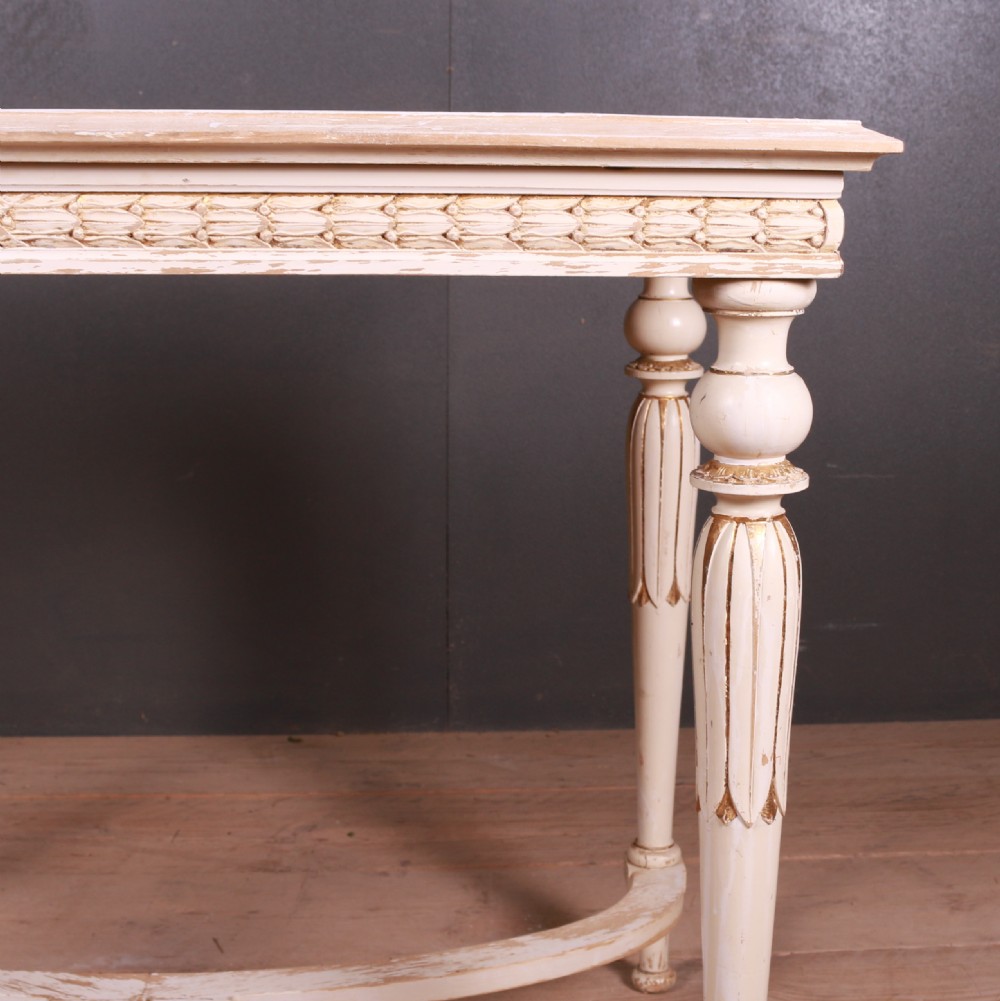 A Gustavian off-white painted lamp table featuring carved frieze detailing, gilt accents, fluted tapered legs, and a curved stretcher base. View III